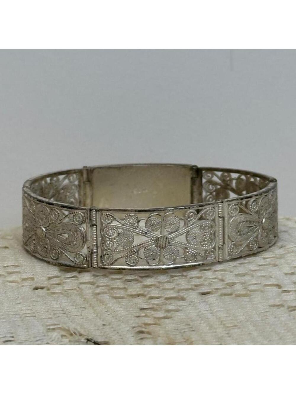 Vintage sterling silver filigree bracelet with floral and scrollwork designs.